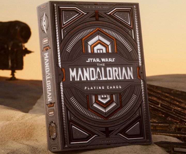 The Mandalorian deck by theory11: a grey box with a silver helmet emblem, standing in desert sand.