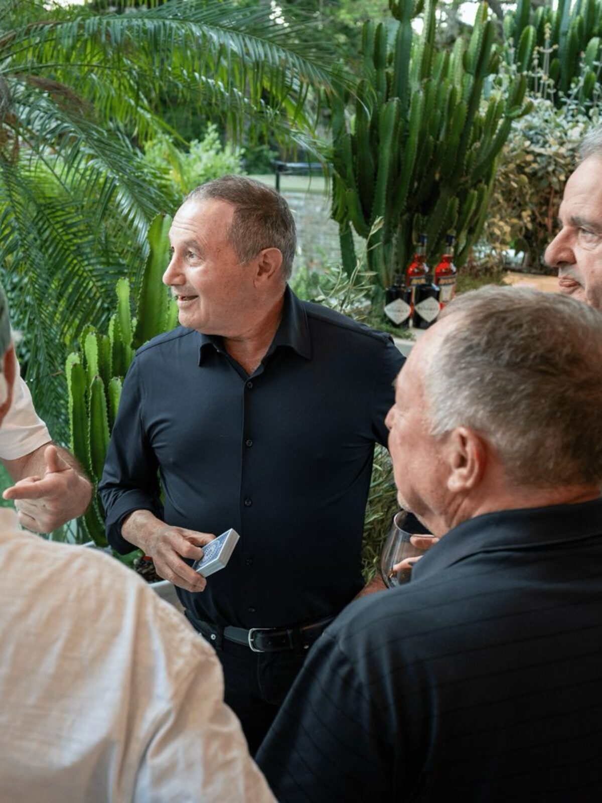 Barry performs close-up card magic for guests gathered around a table.